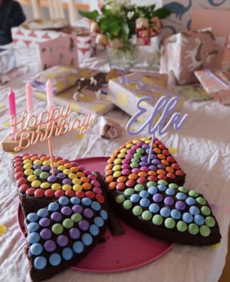 Auf diesem Bild sieht man einen Smarties Kuchen als Schmetterling mit bunten Cake Toppern.